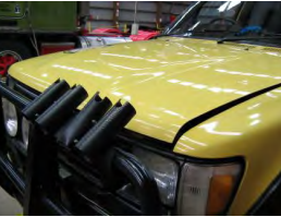Front of a yellow vehicle with a bull bar and fishing rod holders